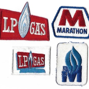 Peut inclure: Quatre patchs brodés, deux rouge et blanc avec le texte "LP GAS" et une flamme bleue, un bleu et rouge avec le texte "MARATHON" et un "M" rouge, et un blanc avec une flamme bleue et un "M"