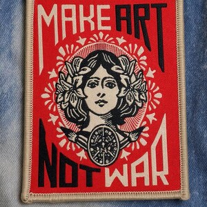 May include: Embroidered patch with a red background and the text "MAKE ART NOT WAR" in white and black. The patch features a woman's face with a laurel wreath and a circular design.