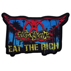 Puede incluir: Un parche bordado negro y amarillo con el texto "Aerosmith Eat The Rich" y un gráfico rojo y azul de palmeras y una estrella.