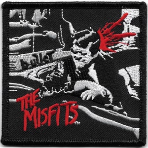 Könnte beinhalten: Schwarzer und weißer gestickter Aufnäher mit einer Grafik einer Person mit einer blutigen Kopfverletzung. Der Text "THE MISFITS" ist in Rot.