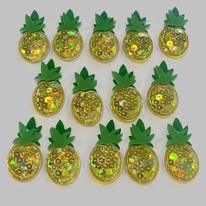 Könnte beinhalten: Ein Set mit 12 regenbogenfarbenen Ananas-Verzierungen mit grünen Blättern. Die Ananas bestehen aus einem holografischen Material, das Licht in verschiedenen Farben reflektiert.