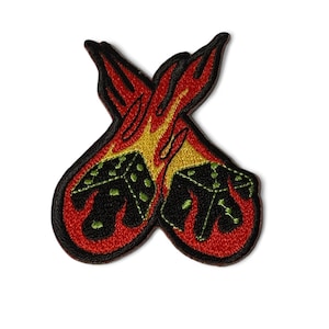 May include: An embroidered patch featuring two black dice on fire, with red and yellow flames. The dice have green dots.