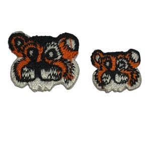 May include: Two embroidered iron-on patches of tiger faces. The larger patch is orange and black with a white background. The smaller patch is the same design but smaller.