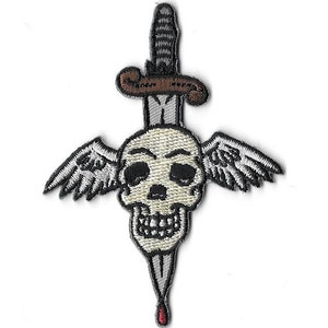 Puede incluir: Una calavera blanca con alas y una daga que la atraviesa. La daga tiene un mango marrón y una hoja plateada. La calavera tiene una sonrisa de dientes y está delineada en negro.