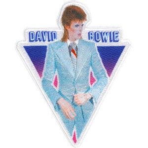 Puede incluir: Un parche triangular blanco con un fondo degradado azul y rosa. El parche presenta una foto de David Bowie con un traje azul claro con una corbata de patrón blanco y azul. El texto "DAVID BOWIE" está bordado en azul en el parche.