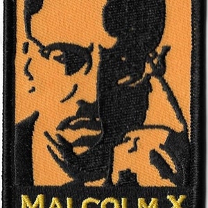 May include: Black and yellow embroidered patch featuring a portrait of Malcolm X with the text "MALCOLM X" below.