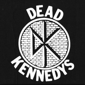 May include: Black and white patch with the text "DEAD KENNEDYS" and a circular symbol with a brick pattern and a stylized X inside.