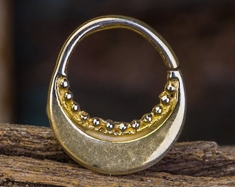 May include: A gold-colored hoop earring with a beaded edge. The hoop is slightly curved and has a smooth, polished finish.