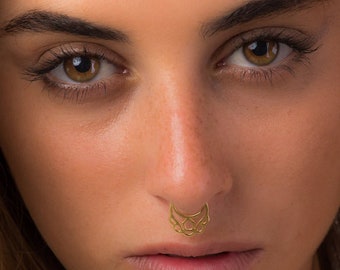 May include: Close-up of a person's face with a gold nose ring. The nose ring is a delicate, intricate design.