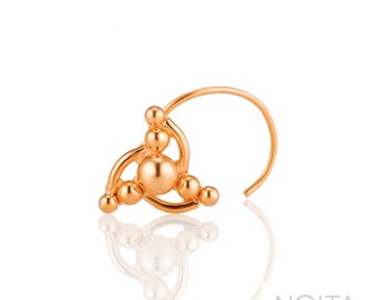 May include: Gold nose ring with a geometric design featuring multiple small spheres. The ring is open and has a curved shape.