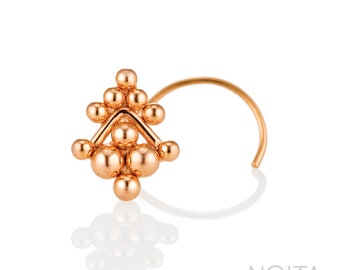 May include: A gold nose ring with a geometric design made of small, round beads. The ring is curved and has a small loop at the end.