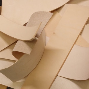 May include: A pile of off-white leather scraps in various shapes and sizes.