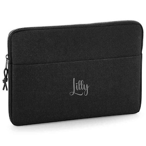 May include: Black laptop sleeve with a zip closure and the name "Lilly" embroidered on the front.