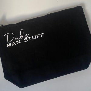 May include: Black canvas zippered pouch with white text that reads "Dad's Man Stuff".