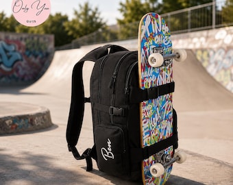 Könnte beinhalten: Ein schwarzer Rucksack mit mehreren Reißverschlussfächern und verstellbaren Riemen, der auf einer Seitentasche den in Weiß gestickten Namen Ben trägt. Ein buntes Skateboard mit blauem, rotem und weißem Graffiti-Text ist hinten befestigt.
