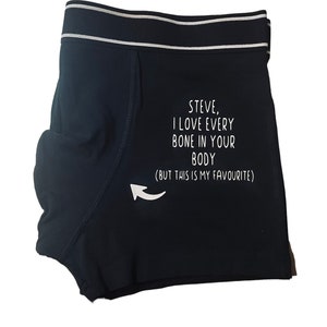 May include: Black boxer shorts with a white and grey striped waistband. The text "STEVE, I LOVE EVERY BONE IN YOUR BODY (BUT THIS IS MY FAVOURITE)" is printed in white. A white arrow points to the right.