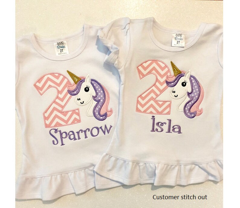 May include: Two white t-shirts with pink and white chevron number 2 and a unicorn with a gold horn, purple mane, and pink ears. One shirt says "Sparrow" and the other says "Isla".