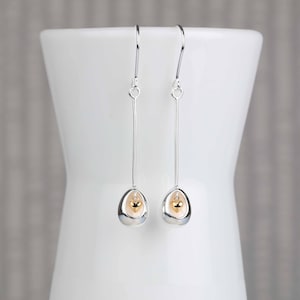 Impresionantes aretes ovalados con corazón colgante en miniatura en plata y oro