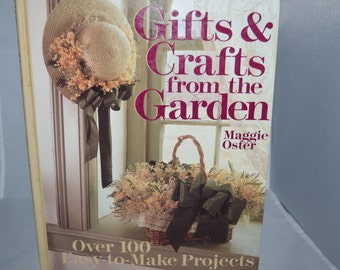 以下が含まれることがあります： マギー・オスター著「Gifts & Crafts from the Garden」の表紙。表紙には、緑のリボンが付いた麦わら帽子と、ドライフラワーと緑のリボンが入った籐のバスケットが描かれています。