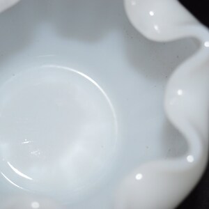 May include: A white ceramic bowl with a ruffled edge. The bowl is empty and has a smooth, glossy finish.
