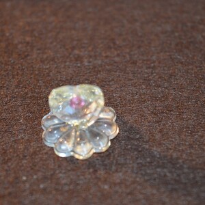 以下が含まれることがあります： 透明なガラス製のハート型の置物で、中央にピンクの宝石があり、透明なガラスの花の模様で囲まれています