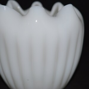 May include: White milk glass vase with a ruffled top and vertical ridges.