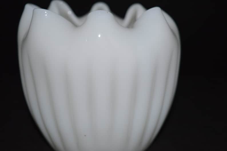 May include: White milk glass vase with a ruffled top and vertical ridges.