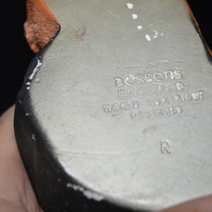 Puede incluir: Primer plano de la parte inferior de una figurita de cer&aacute;mica. La parte inferior es plateada con un borde negro y el texto "Bossons England World Copyright Reserved R" est&aacute; impreso en la parte inferior.