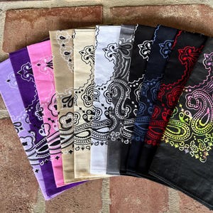 Puede incluir: Una colecci&oacute;n de diez pa&ntilde;uelos cuadrados dispuestos en abanico, cada uno con un patr&oacute;n de cachemira tradicional. Los colores incluyen morado claro, morado oscuro, rosa, beige, crema, blanco, gris, azul marino, negro con detalles rojos y negro con un degradado arco&iacute;ris.