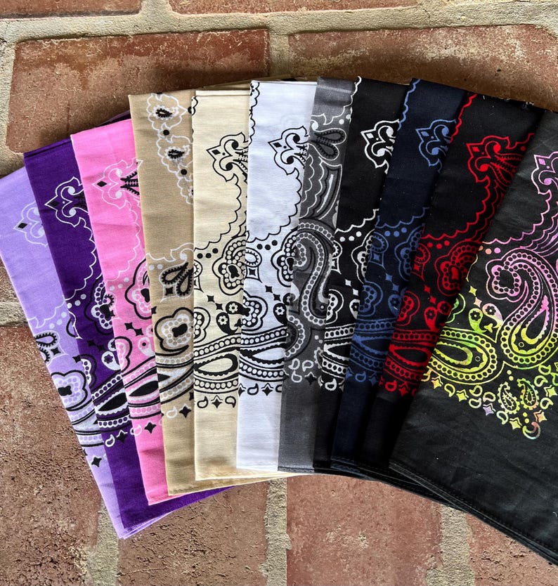 Puede incluir: Una colecci&oacute;n de diez pa&ntilde;uelos cuadrados dispuestos en abanico, cada uno con un patr&oacute;n de cachemira tradicional. Los colores incluyen morado claro, morado oscuro, rosa, beige, crema, blanco, gris, azul marino, negro con detalles rojos y negro con un degradado arco&iacute;ris.