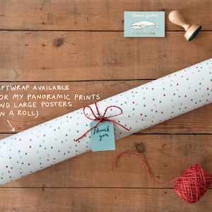 May include: A roll of white wrapping paper with a pattern of small green and red triangles. The paper is tied with twine and a small blue tag that says "Thank you".