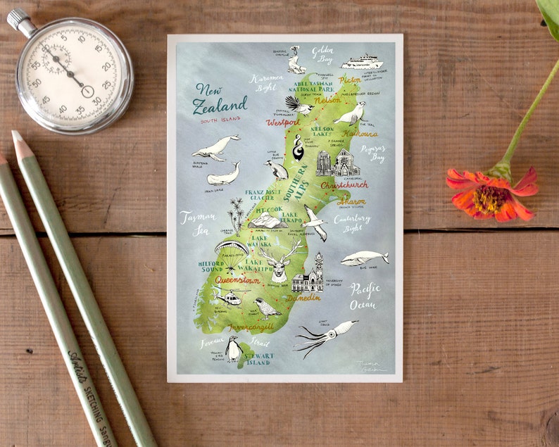 May include: A hand-drawn map of New Zealand with illustrations of animals, landmarks, and cities. The map is on a blue background with green and brown accents. The text "New Zealand" is written in a cursive font at the top of the map.