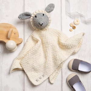 May include: A white knitted baby blanket with a gray knitted lamb head attached. The blanket is soft and cuddly, perfect for a baby.