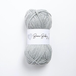 May include: A skein of light gray yarn with the label "Beau Baby" on it.