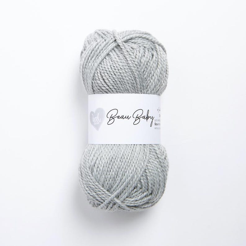 May include: A skein of light gray yarn with the label "Beau Baby" on it.