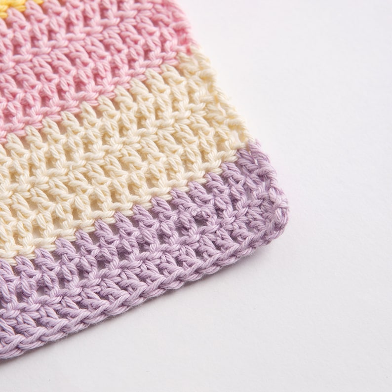 May include: A crocheted textile featuring horizontal stripes in pastel colors. The pattern consists of rows of light pink, cream, and light purple yarn, worked in a consistent stitch that creates a textured, open-weave fabric with visible loops.