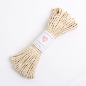 May include: A beige 5mm macrame rope made in Turkey with 90% cotton and 10% polyester. The label reads "Handwash Only".