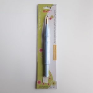 Pode incluir: Uma ferramenta de punção de agulha azul com uma ponta de agulha dourada, embalada em um fundo verde e branco com o texto "SKC Punch Needle Set" e "Needle Punching is...easy to start and impossible to stop! QUALITY PRODUCT".