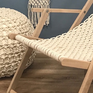 May include: A white macrame chair with a wooden frame. The chair is made of thick rope and has a relaxed, bohemian style.