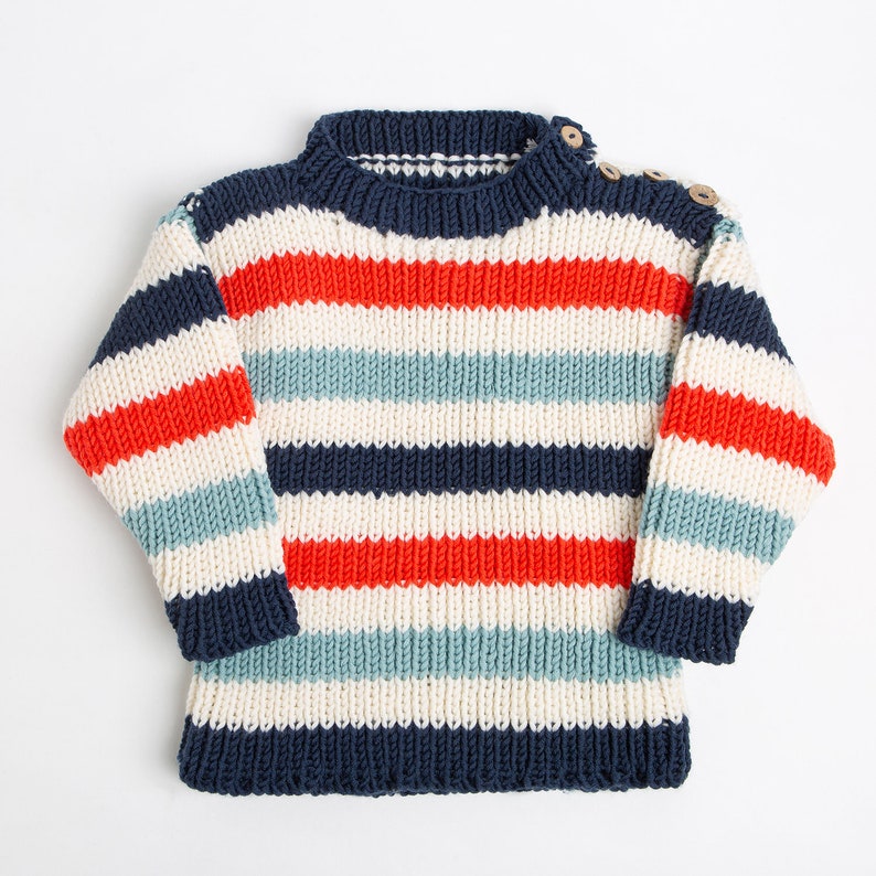 May include: A striped knitted jumper in red, blue, white and cream colours. The jumper has a round neckline and long sleeves.