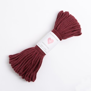 May include: A roll of 5mm maroon macrame rope, made in Turkey from 95% cotton and 5% polyester. The label reads "Handwash Only" and "5mm Macrame Rope".