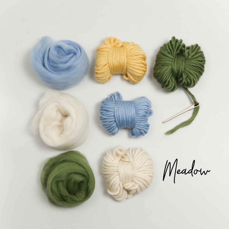 Pode incluir: Um conjunto de fio e l&atilde; para feltro de agulha, incluindo tons de azul, verde, amarelo e branco. O texto "Meadow" est&aacute; escrito em preto sobre um fundo branco.