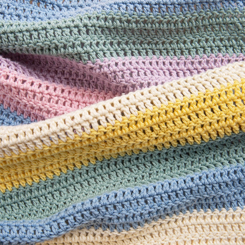 May include: A crocheted blanket featuring horizontal stripes in soft pastel colors including light blue, sage green, lavender, pale pink, cream, and sunny yellow. The fabric displays a consistent double crochet stitch pattern with a textured finish.