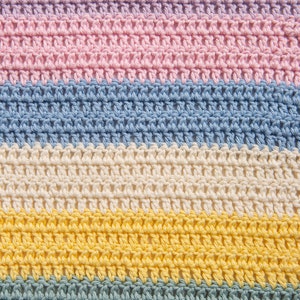 May include: A crocheted fabric featuring horizontal stripes in pastel colors. The pattern consists of repeating rows of double crochet stitches in light pink, soft blue, cream, bright yellow, and muted sage green, creating a textured surface.