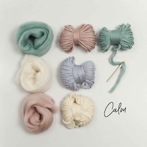 Pode incluir: Um conjunto de seis novelos de l&atilde; em v&aacute;rios tons de azul, rosa e branco. A l&atilde; est&aacute; disposta em c&iacute;rculo sobre um fundo branco. A palavra "Calm" est&aacute; escrita em it&aacute;lico preto no canto inferior direito da imagem.