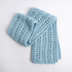 Puede incluir: Una bufanda de crochet azul claro con un patr&oacute;n texturizado.