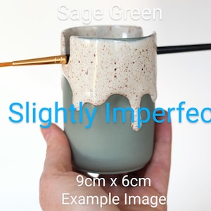 Könnte beinhalten: Grünlicher Keramik-Pinselhalter mit gesprenkeltem weißen Überzug. Der Überzug ist an den Seiten des Halters heruntergelaufen und erzeugt so einen einzigartigen und leicht unvollkommenen Look. Der Halter ist 9 cm x 6 cm groß.