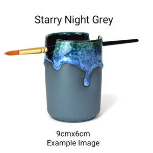 May include: A gray ceramic brush holder with a blue and green glaze. The glaze has a drip effect. The holder is 9cm x 6cm.  Starry Night Grey.