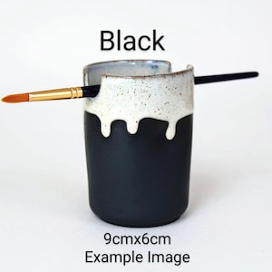 May include: Black ceramic brush holder with a white drip glaze. The holder is 9cm x 6cm and has a brush resting on the rim.
