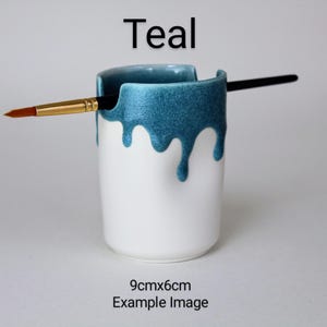 May include: Teal ceramic brush holder with a drip glaze design. The holder is 9cm x 6cm and is shown with a paintbrush.